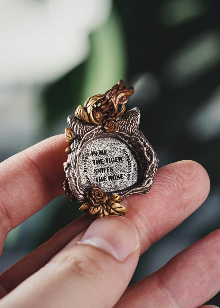 Intricate metal pendant with quote held by a hand, capturing detail and sentiment.